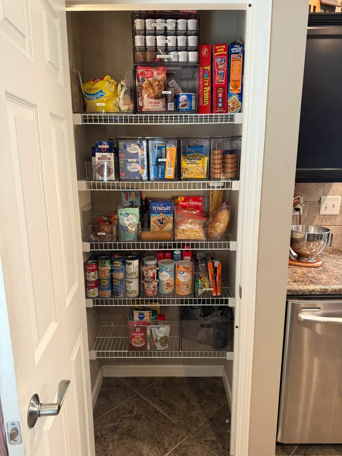 Same actual pantry after, with clear category bins and open floor